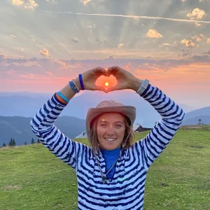 Nella foto si vede Anna, mentre fa un cuore con le mani nella natura incontaminata della montagna.